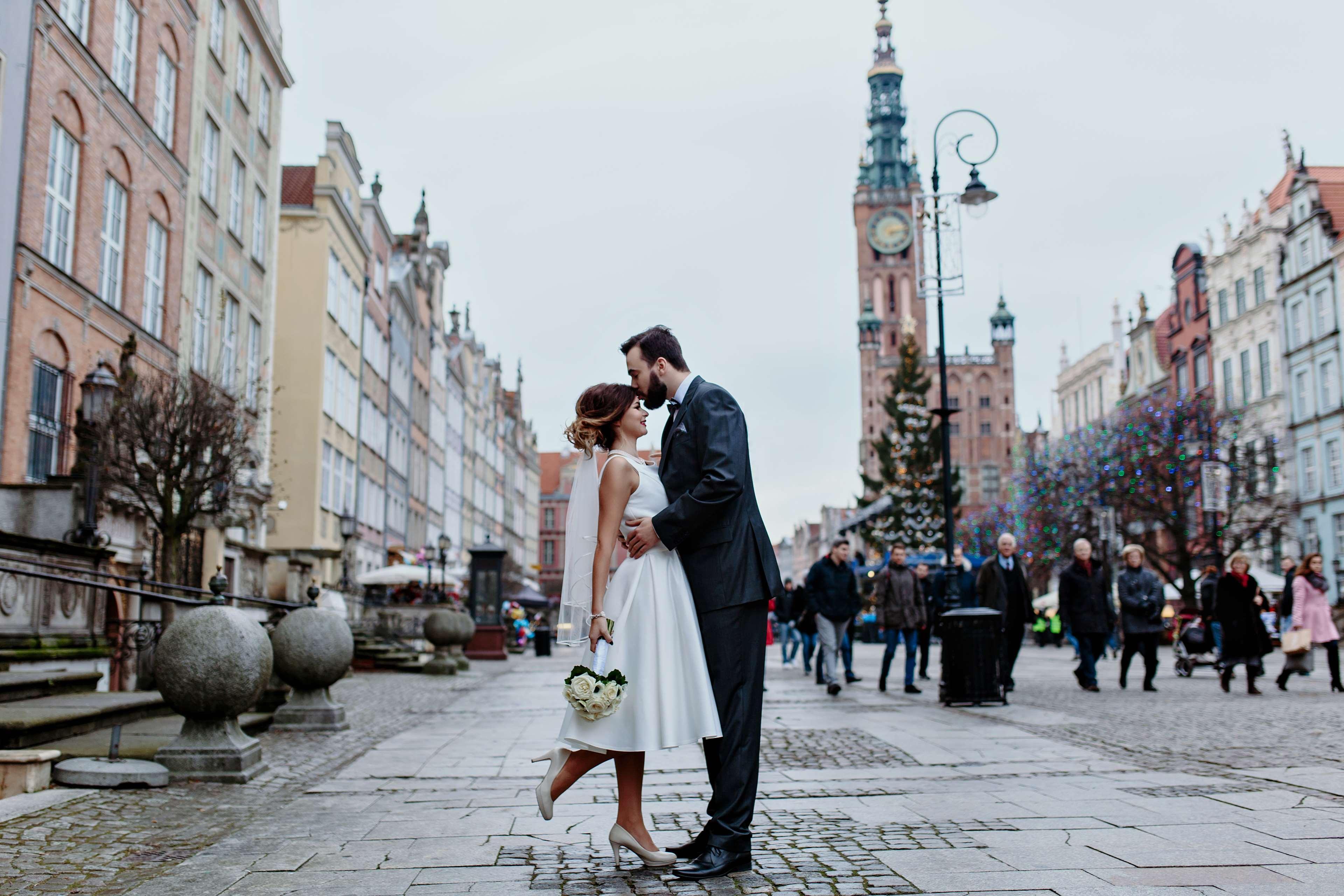 Radisson Blu Hotel, Gdansk Bagian luar foto The photo depicts a joyful moment between a couple in a romantic embrace on a lively street. The woman is wearing a white wedding dress, and the man is dressed in a smart suit. They appear to be celebrating their love, possibly on their wedding day. 