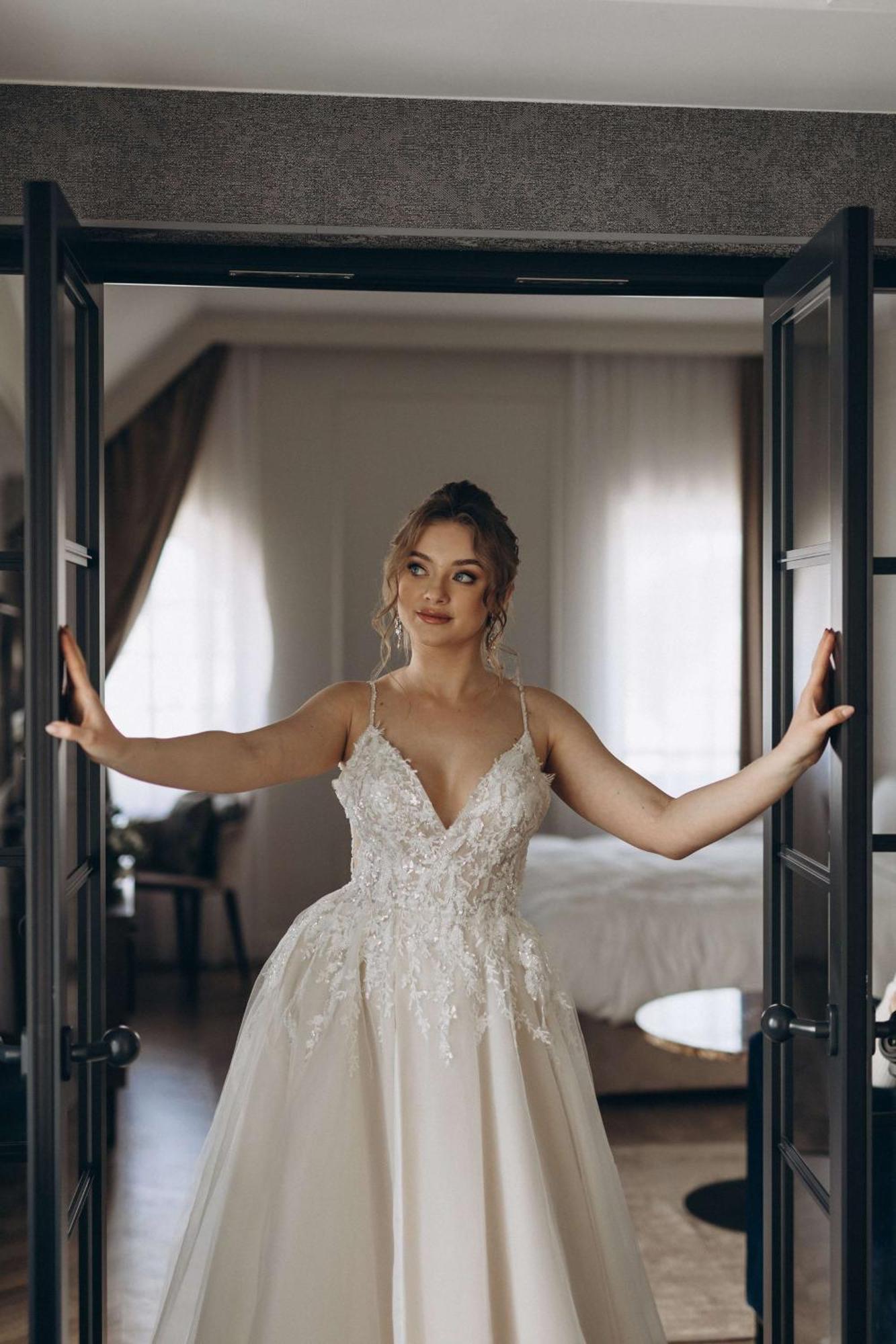 Radisson Blu Hotel, Gdansk Bagian luar foto The photo shows a young woman standing between two open doors. She is wearing a beautiful wedding gown adorned with intricate details. Her hair is styled elegantly, and she has a thoughtful expression on her face. The setting appears to be a stylish 